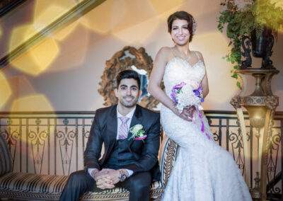 A bride and groom posing in front of a staircase.