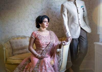 An indian bride and groom posing in front of a window.