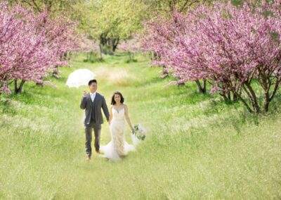 CineCrown wedding bride and groom walking through a field of pink flowers.
