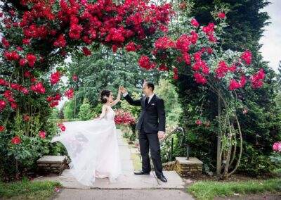 CineCrown wedding photo A bride and groom pose in front of a rose garden.