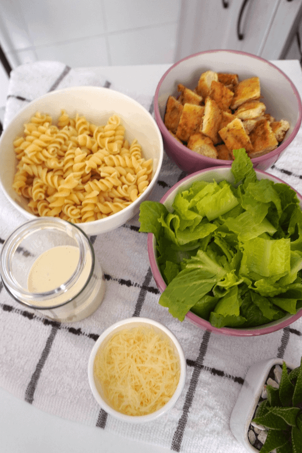 Recipiente de meal prep con ensalada César con pasta alta en proteína lista para llevar.