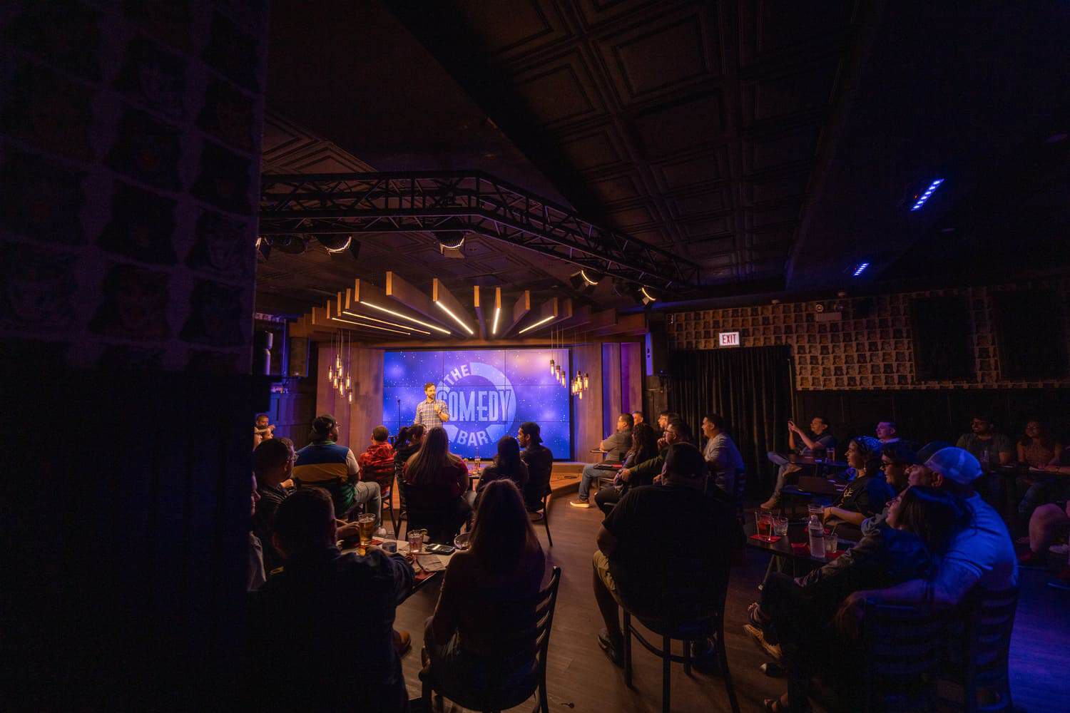 Comedian on stage at The Comedy Bar with audience at tables watching