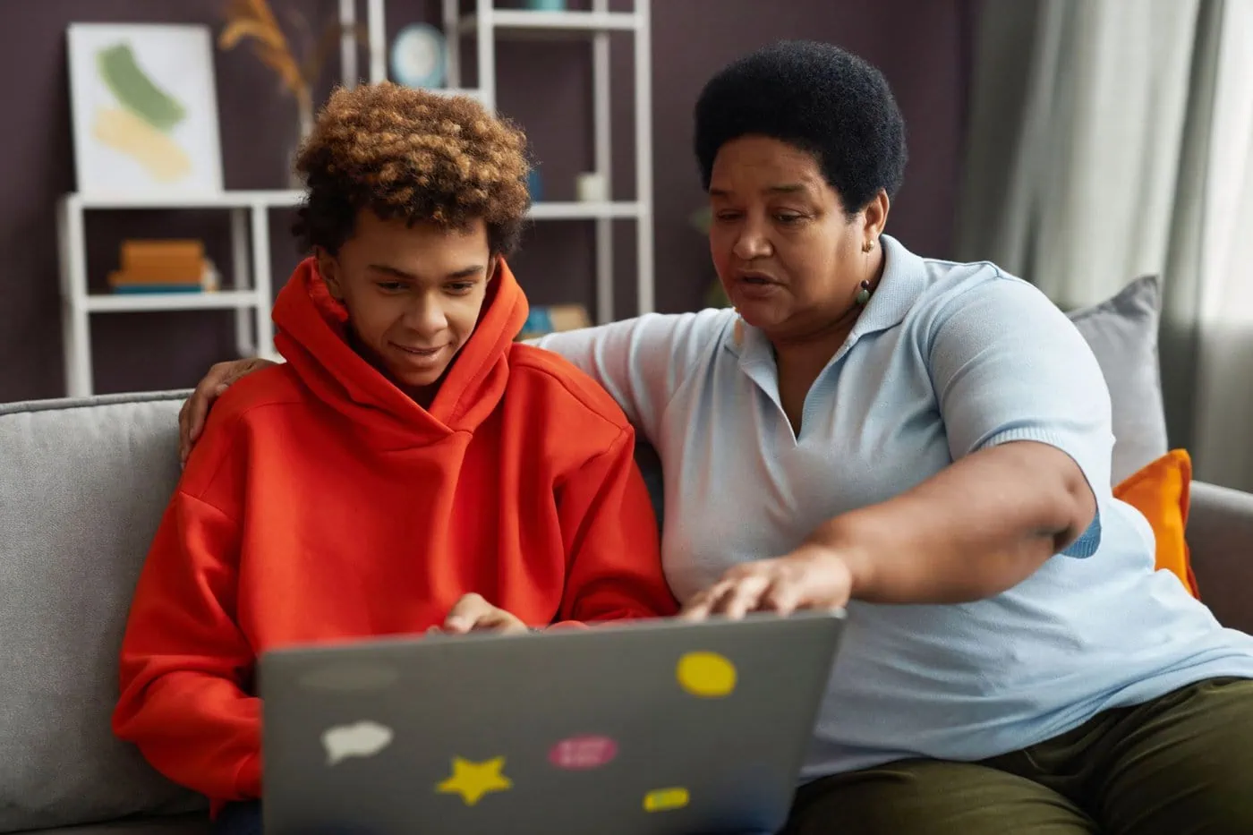 Image of mother and son looking at laptop while sitting on couch.