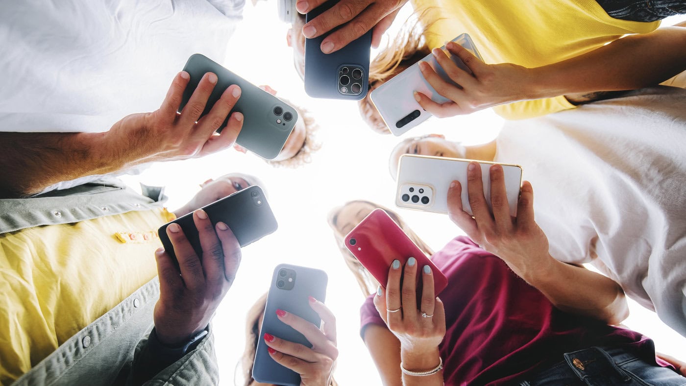 Image of teens in circle holding smart mobile phones
