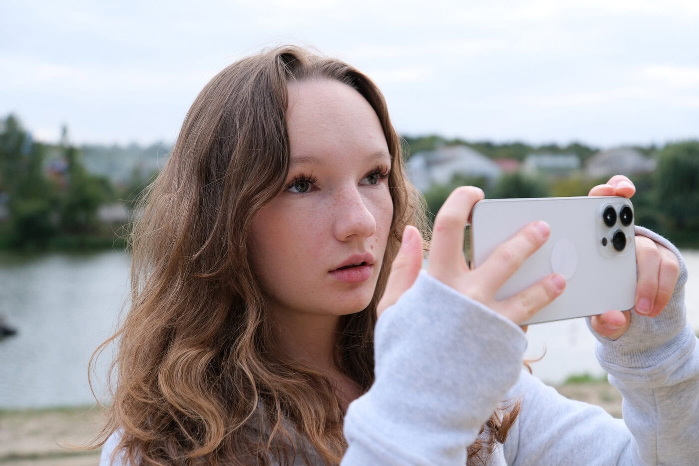 Image of a girl taking photo on mobile phone of sea view.