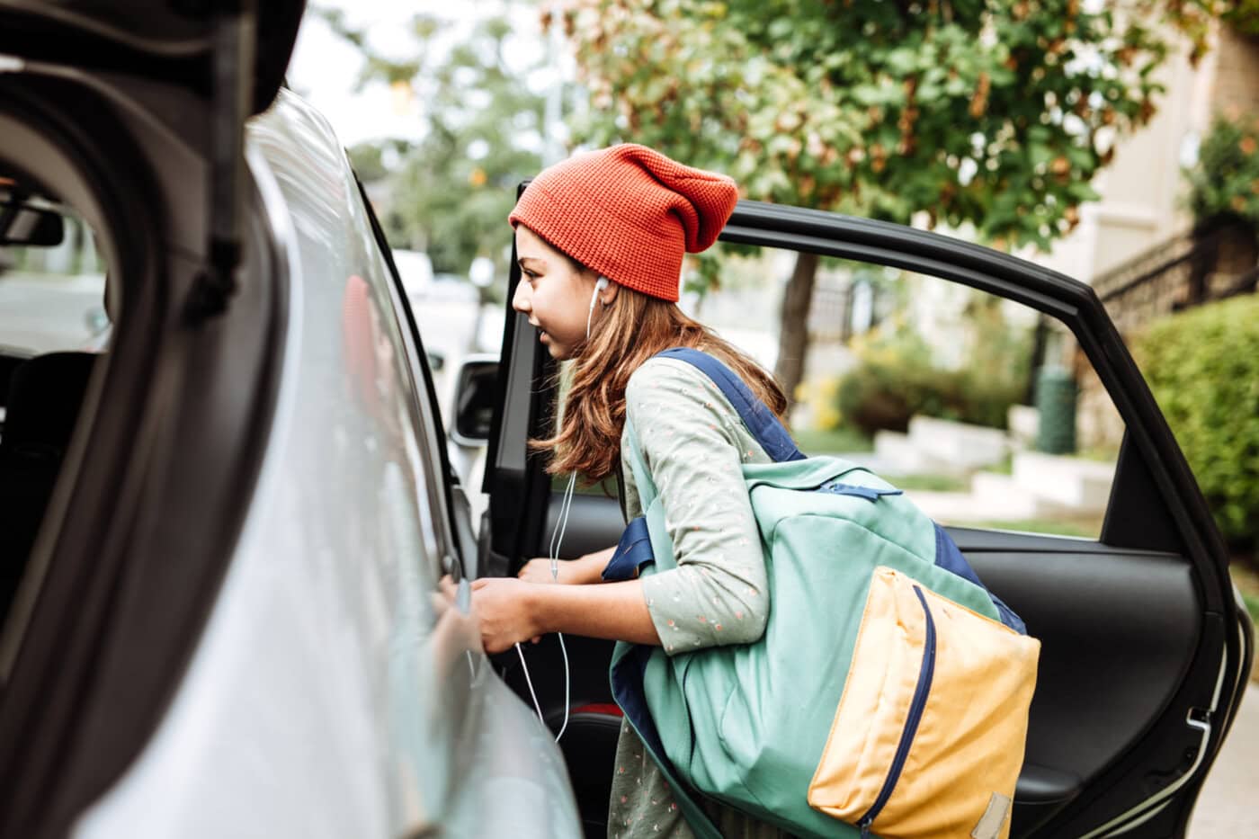 image of Teen getting into car with backpack over one shoulder