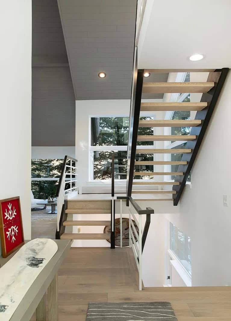Contemporary staircase with light wood steps and black and white railing inside a modern home.