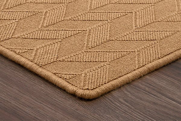 Soft beige textured area rug with geometric pattern on hardwood floor.