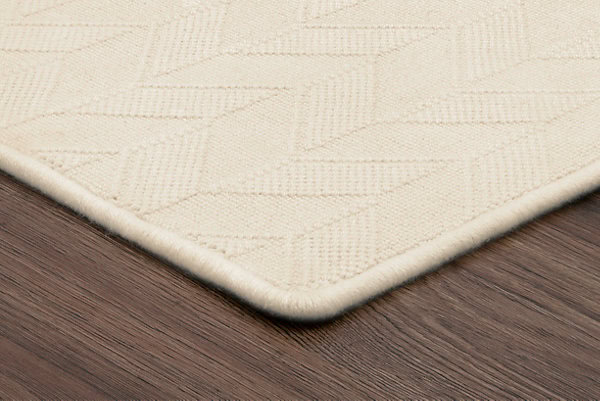 Silky beige carpet with geometric pattern on hardwood floor in modern interior.