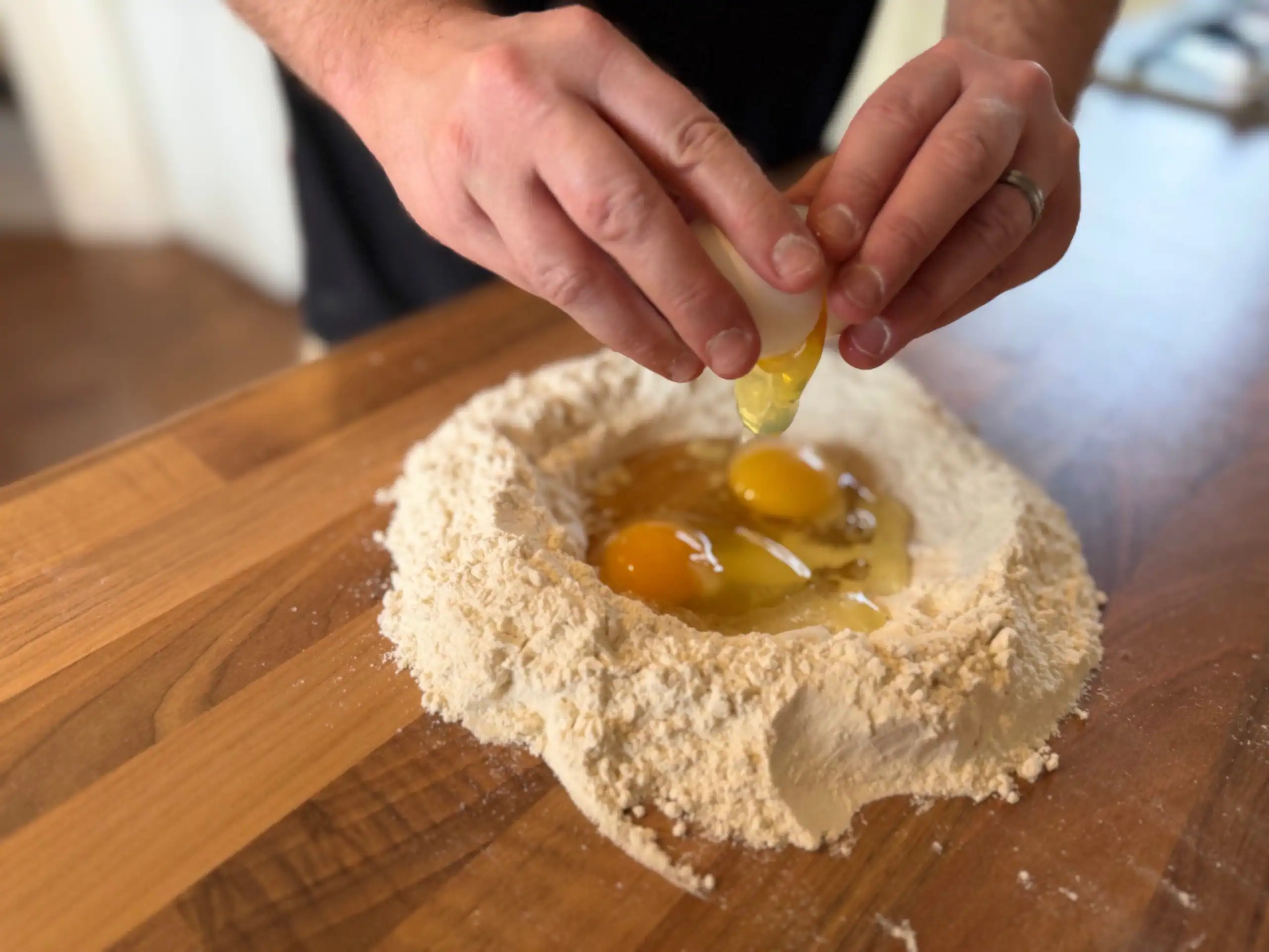 cracking 3 eggs into flour