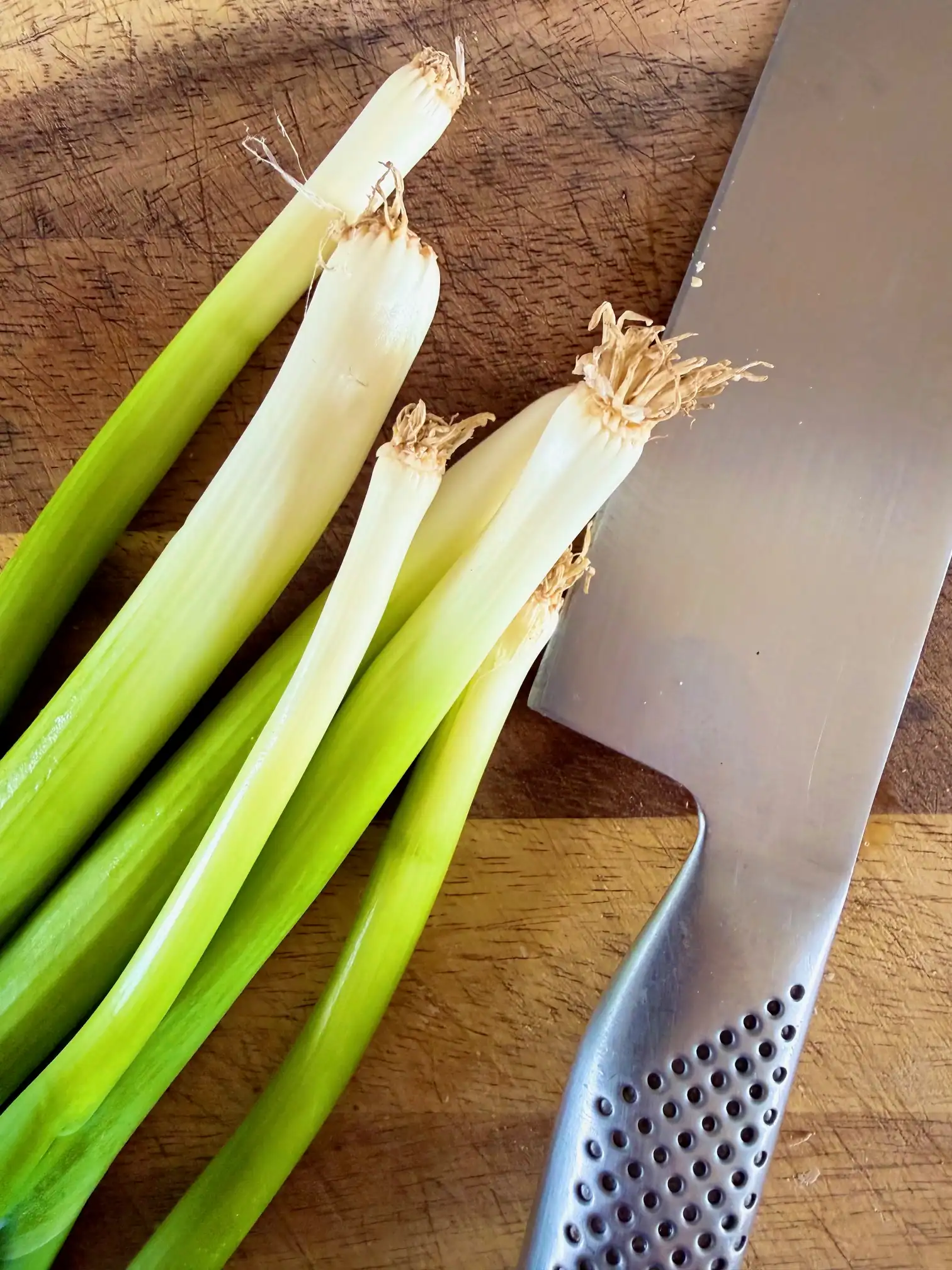 spring onions and a knife on a chopping board
