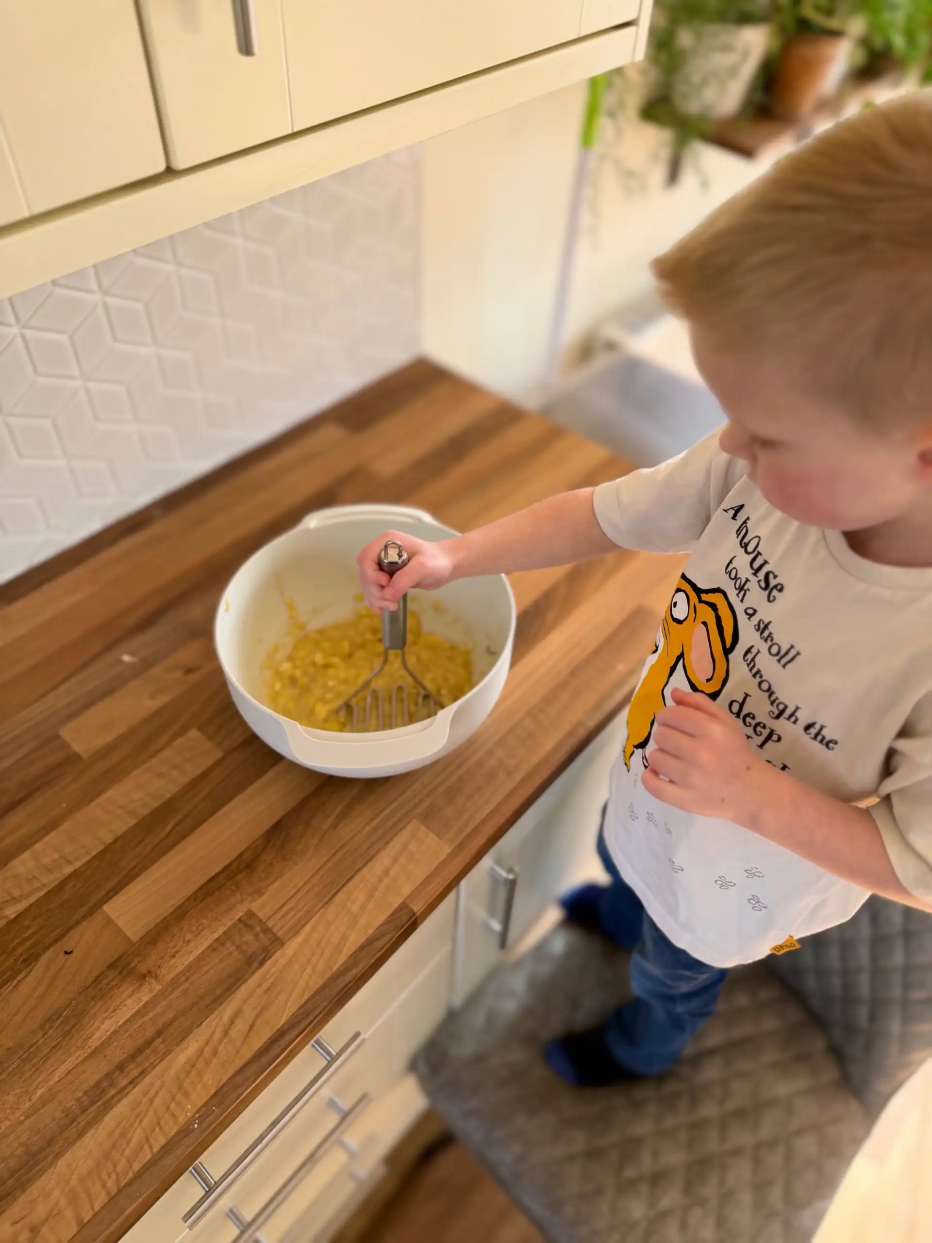 boy mashing bananas for banana bread muffins