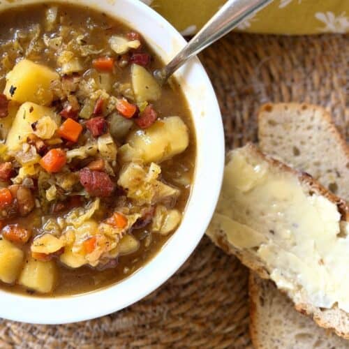 Irish bacon, cabbage and potato soup in a bowl with buttered bread