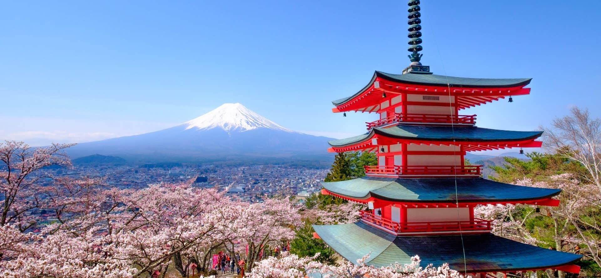 Traditional Japanese pagoda with Mount Fuji and cherry blossoms in the background.