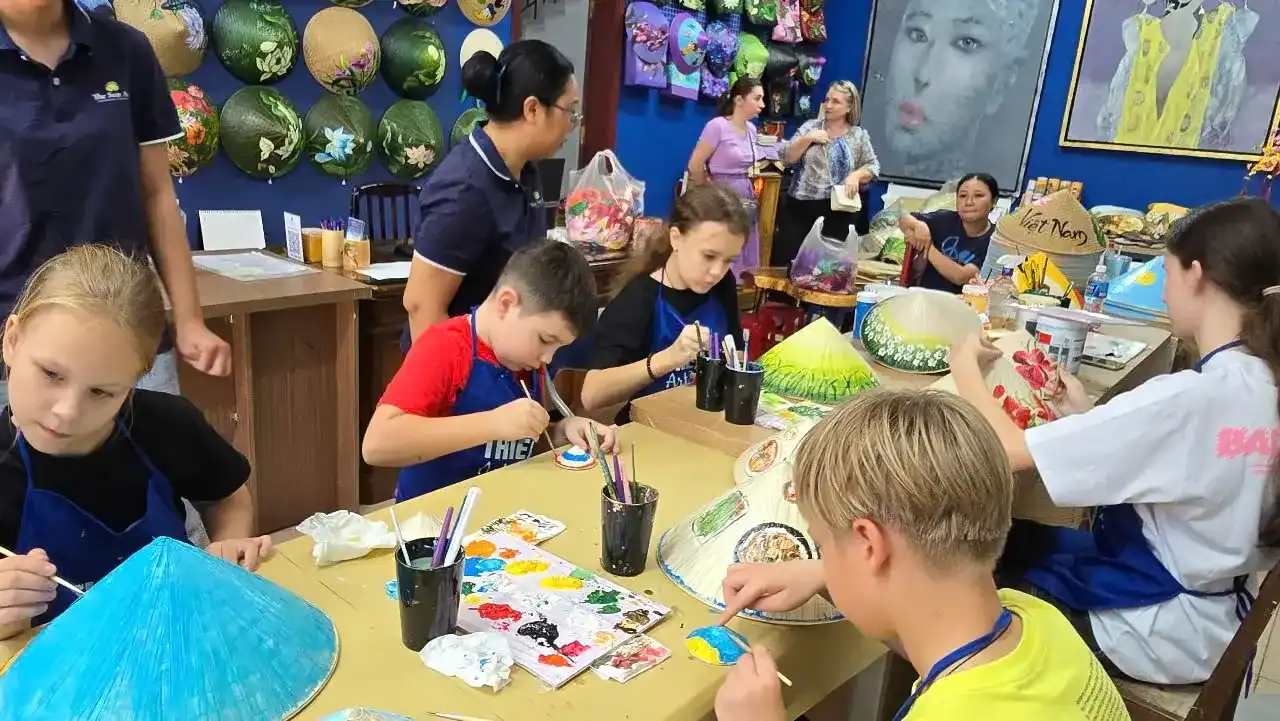 International guests joining a conical hat painting workshop and creating handmade souvenirs in Vietnam