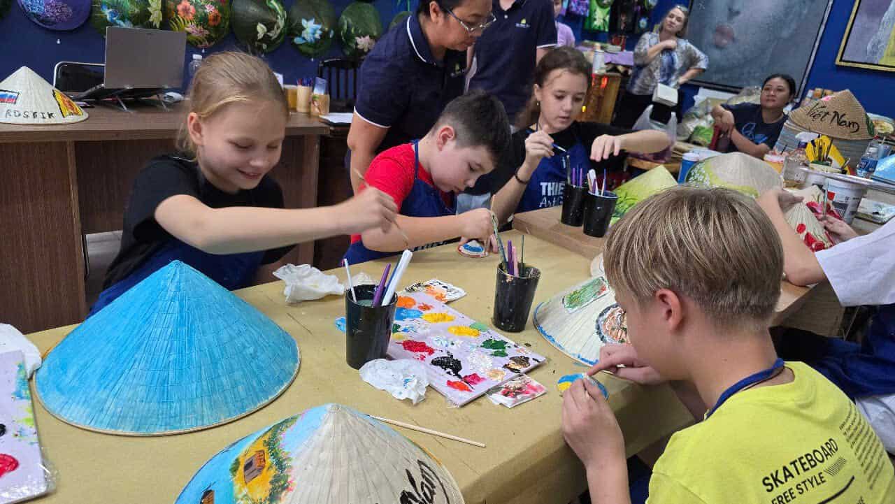 Children painting Vietnamese conical hats during a Dasaque craft workshop in Ho Chi Minh City Kids joining a Vietnamese conical hat painting workshop with Dasaque