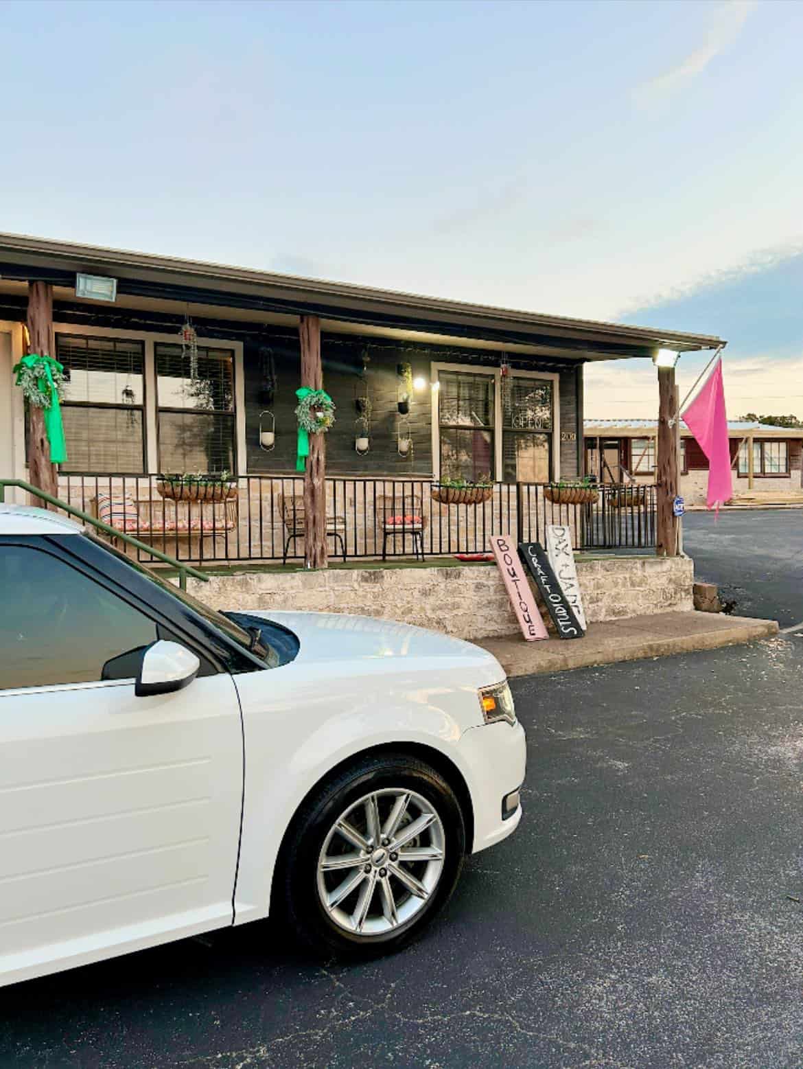 Outdoor cafe with festive green decorations and parking lot.