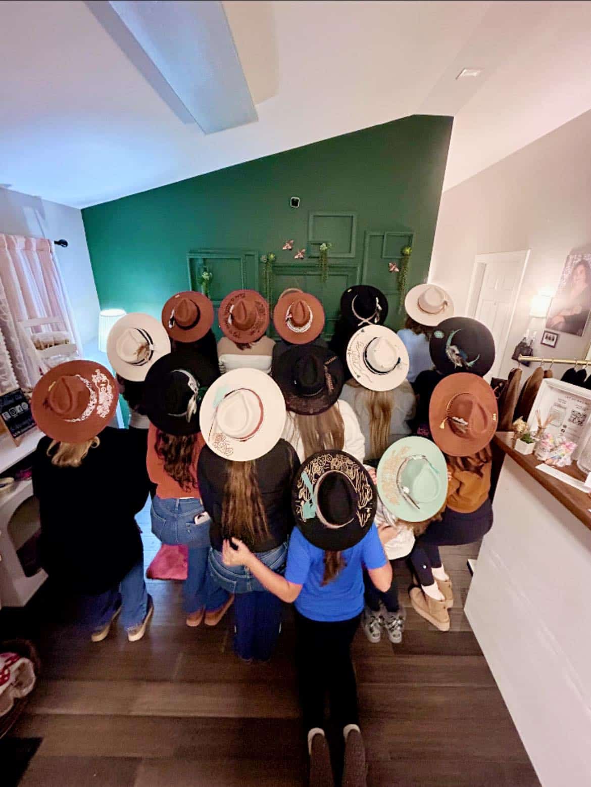 Group of women wearing stylish hats in a cozy boutique setting.