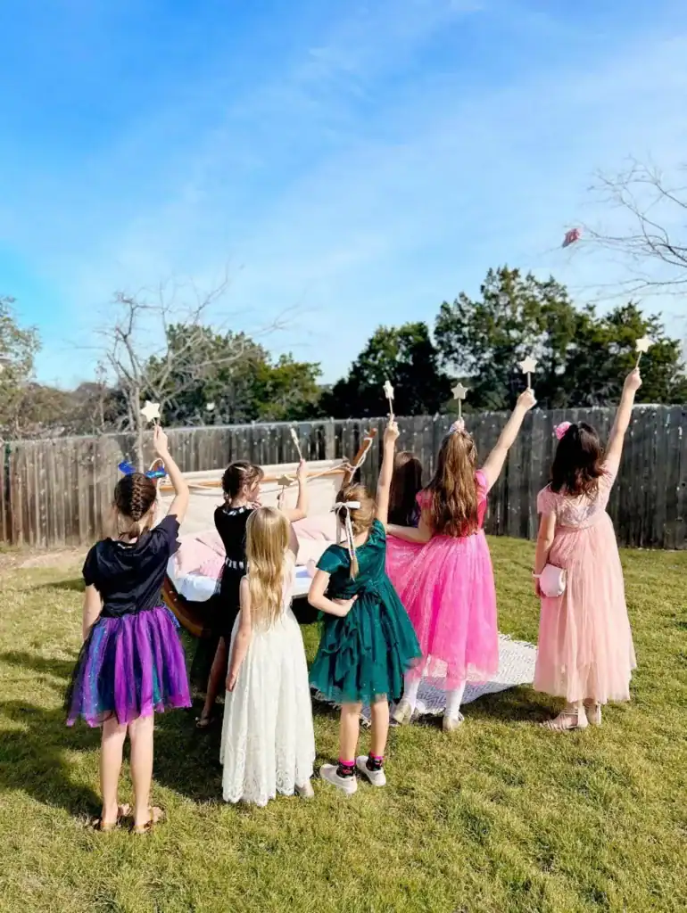 Children in vibrant dresses at a birthday party outside.