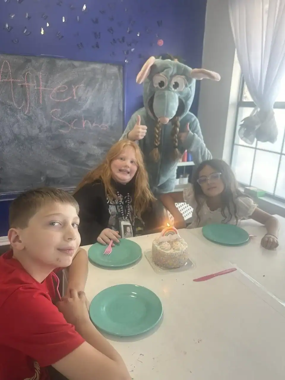 Celebrating a birthday with kids and a mascot at an after school program event.