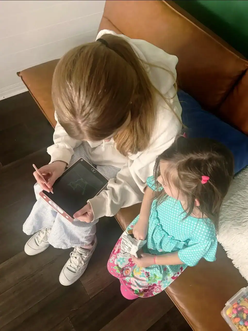 Child and caregiver engaging with educational tablet activity.