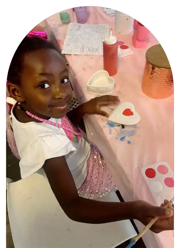 Kids painting heart-shaped designs at a camp art station.
