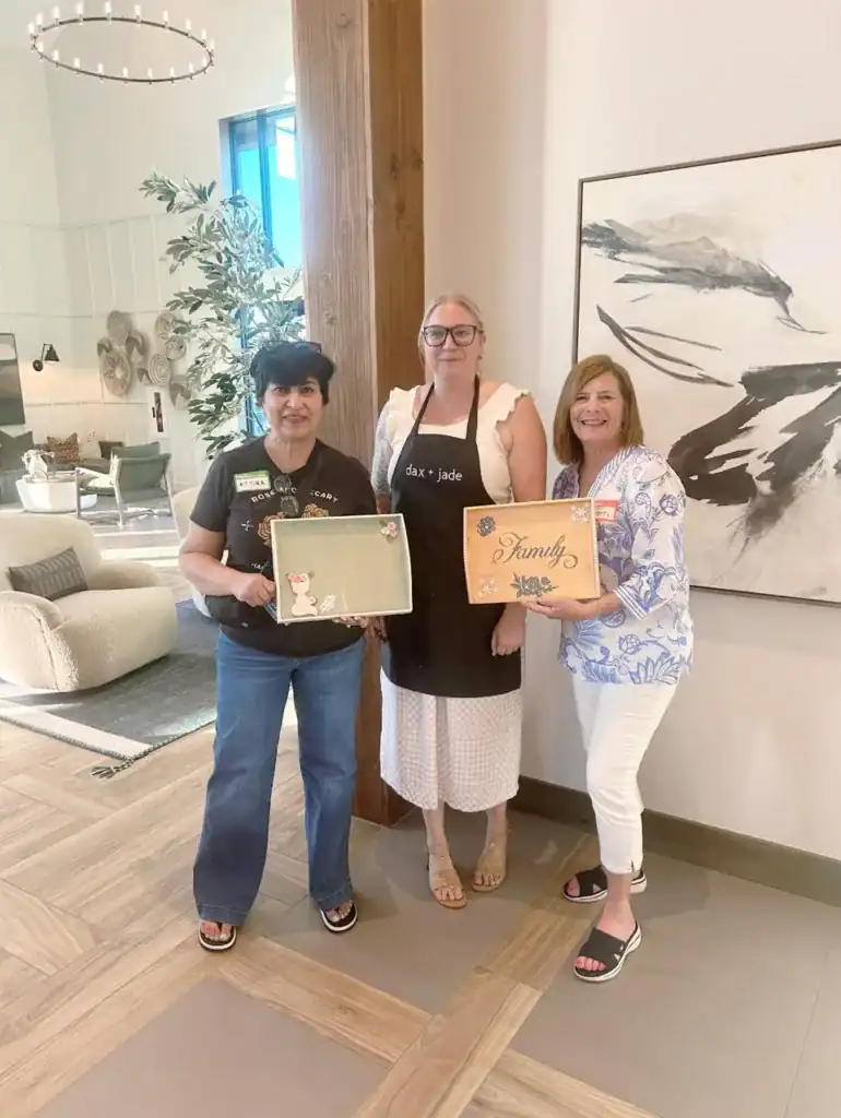 Elegant women holding decorative signs at dax + jade store in a modern interior.