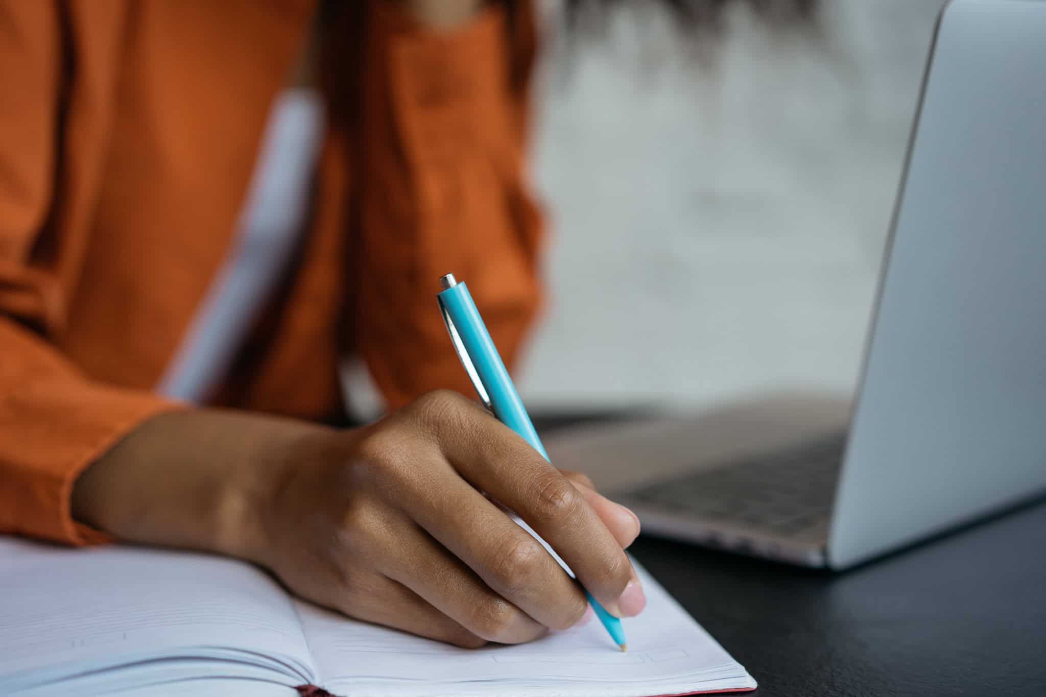 woman writing on a note using a blue pen