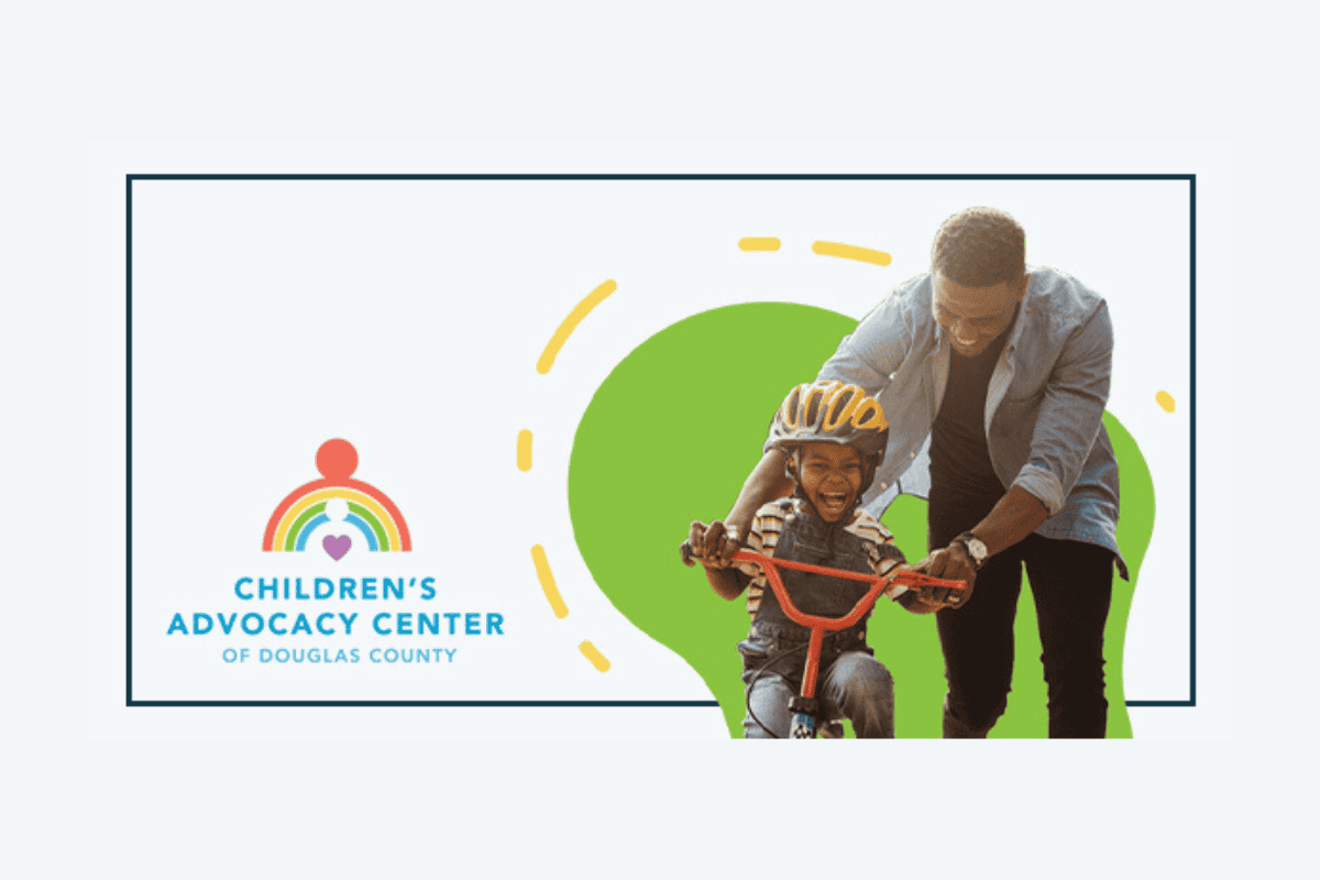 A young child wearing a helmet rides a bike with an adult assisting, symbolizing support and safety at the Children's Advocacy Center of Douglas County.