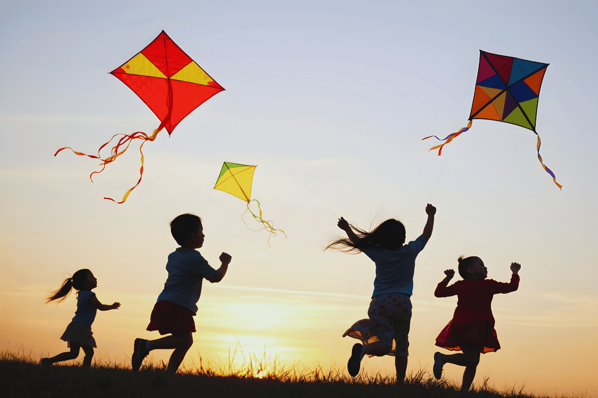 Kite flying children enjoying a sunset outdoors with colorful kites in the sky.