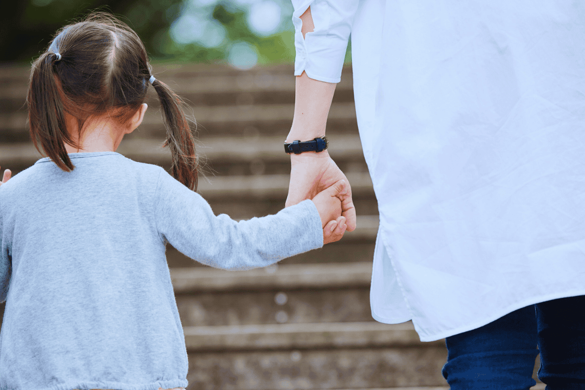 A young girl holding hands with an adult, symbolizing trust and support in foster care.