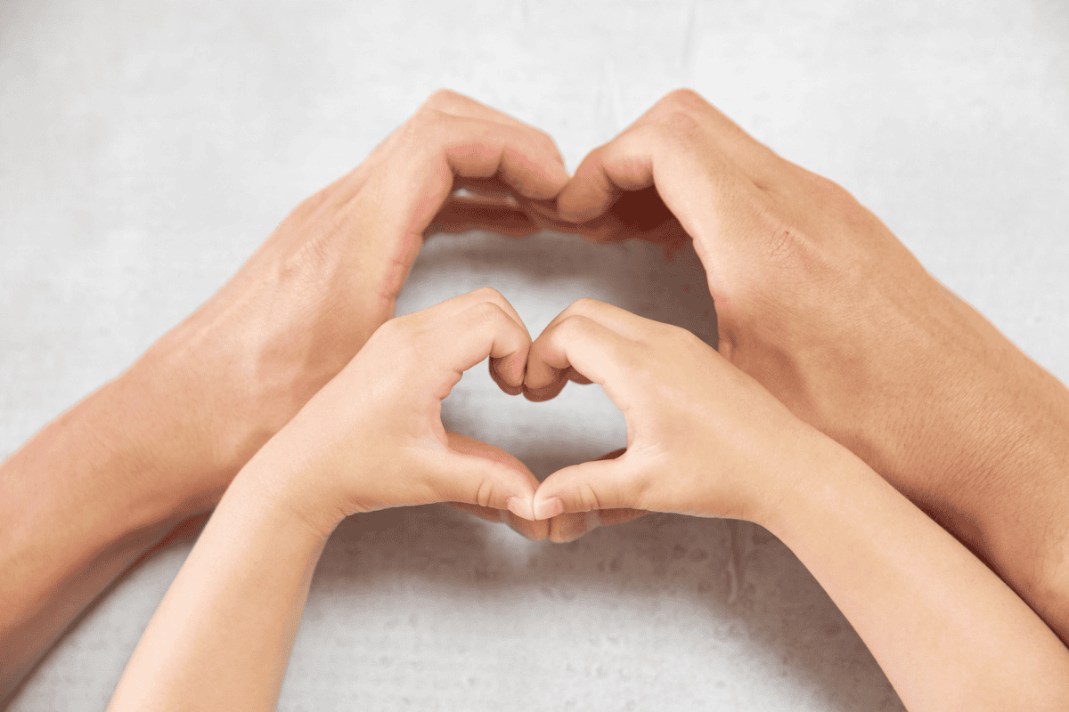 Close-up of two pairs of hands forming a heart shape, symbolizing appreciation and support during Volunteer Appreciation Month.