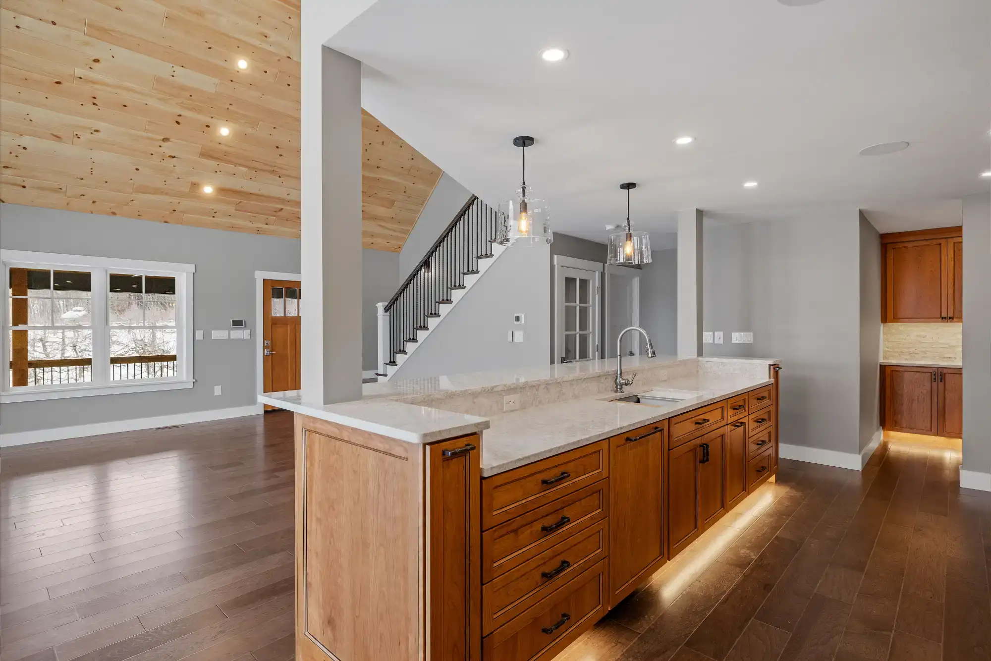 Spacious kitchen featuring wooden cabinets, marble countertops, and modern lighting.