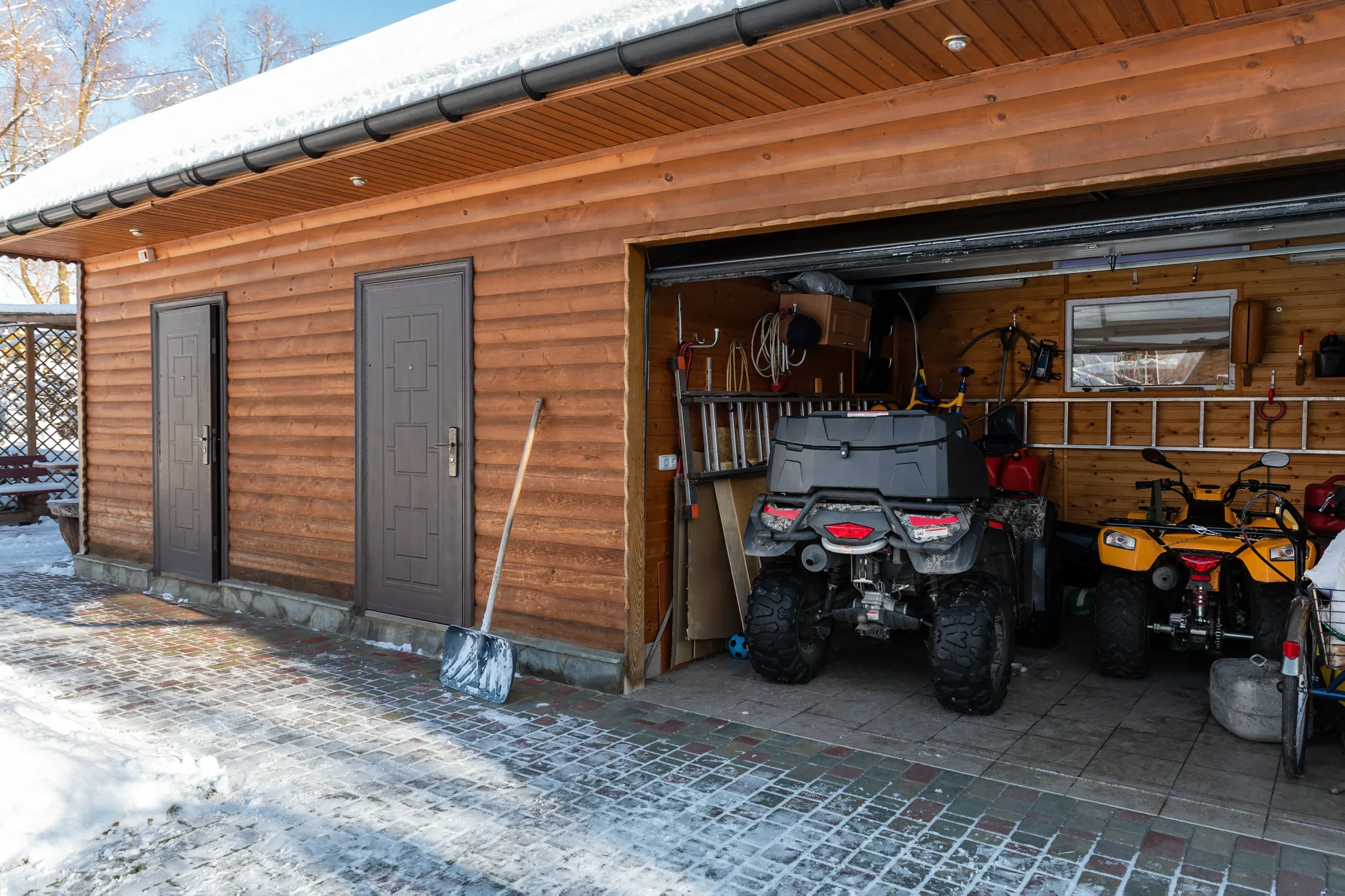 Outdoor garage with storage space, vehicles, and tools in a wooden structure during winter.