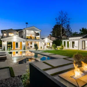 Modern house with pool, fire pit, and manicured lawn at dusk