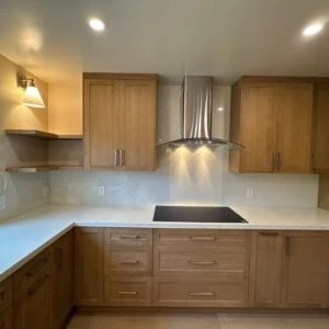 Modern kitchen with light wood cabinets, white countertops, and stainless steel appliances.