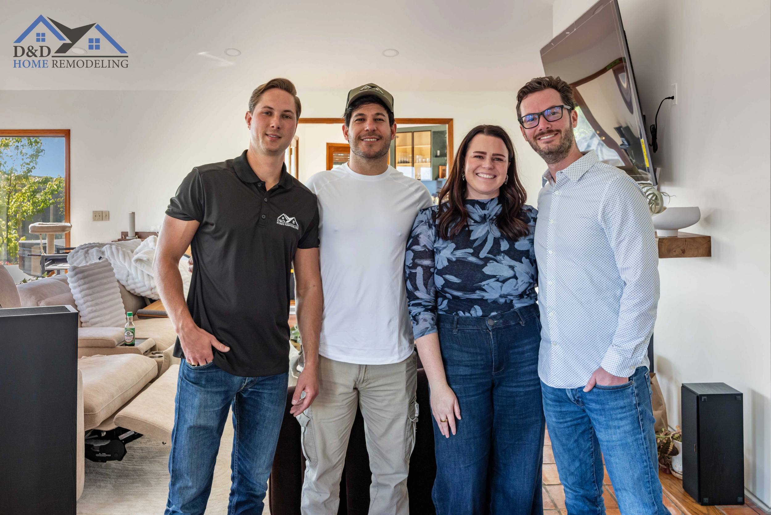 Four people standing together in a modern living room, smiling at the camera.