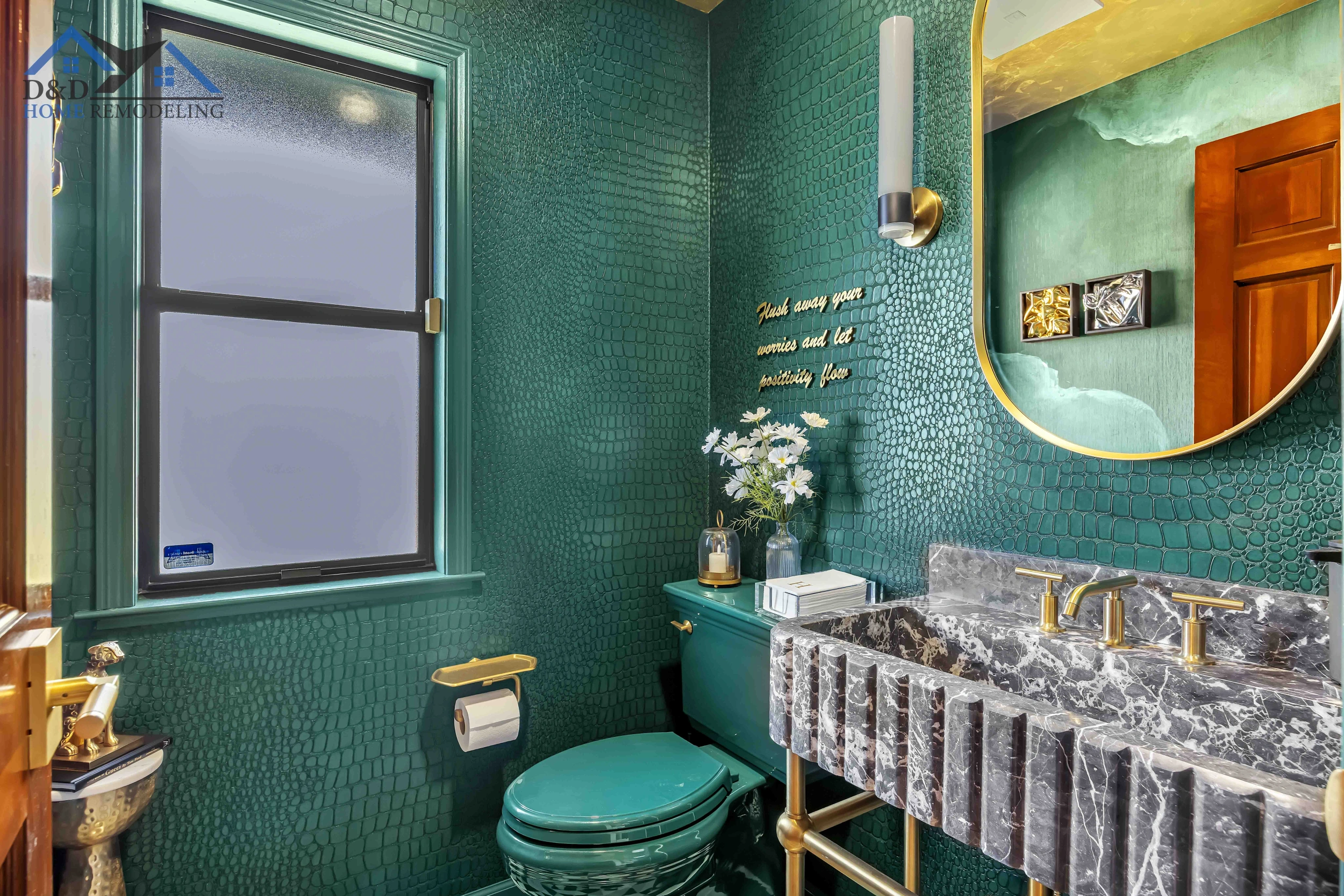 Green bathroom with a dark marble sink and a gold mirror