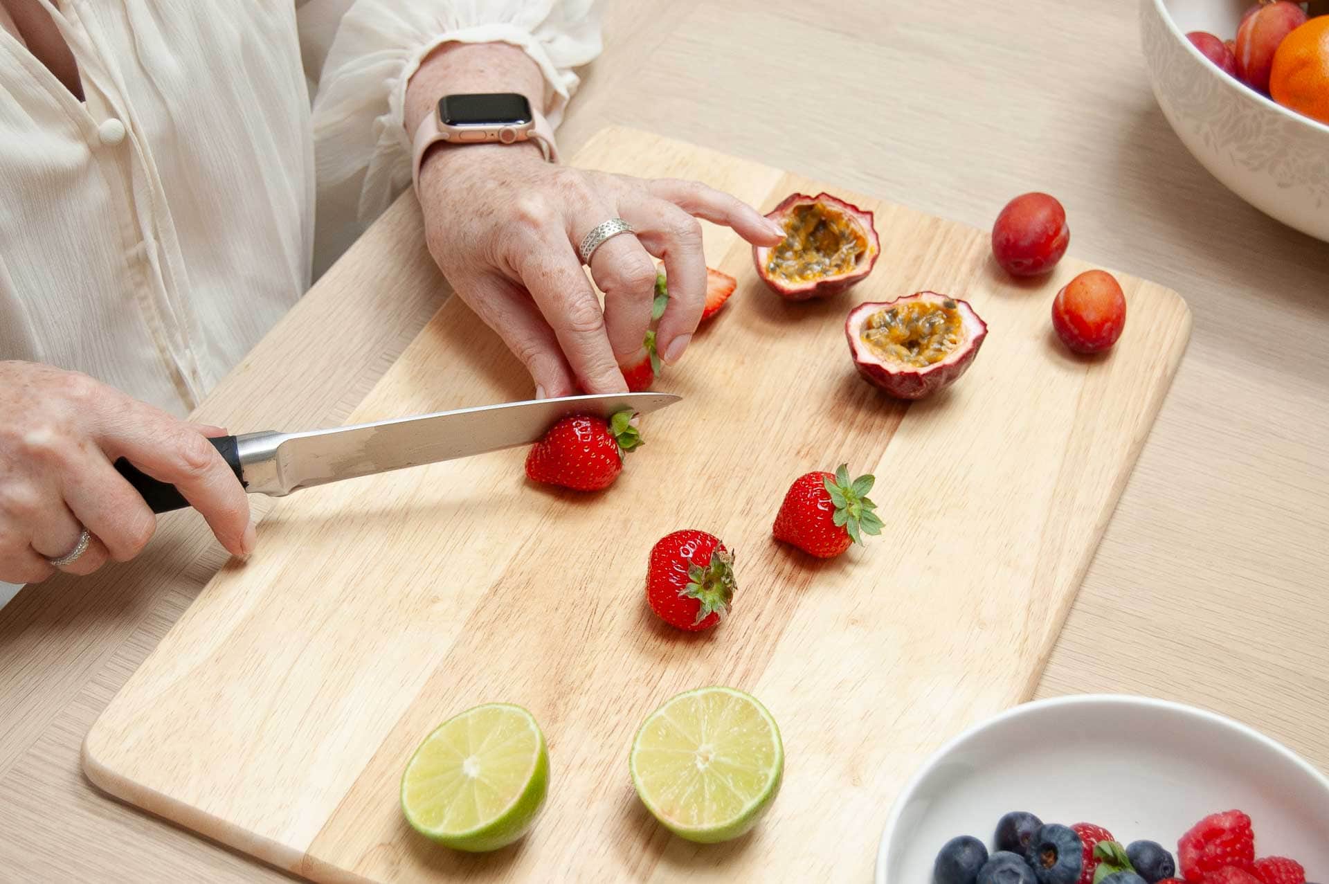 Close-up of Deirdre Egan slicing strawberries and passionfruit for a nourishing recipe