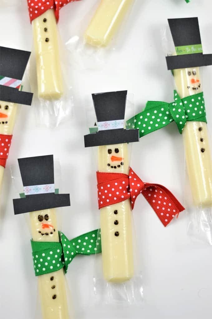 Snowman string cheese decorated with scarves and buttons — easy winter snack