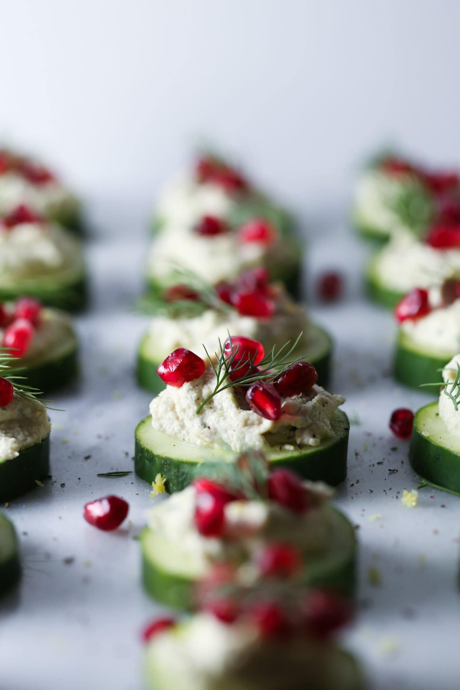 Cucumber bites topped with herby cashew cheese and pomegranate.