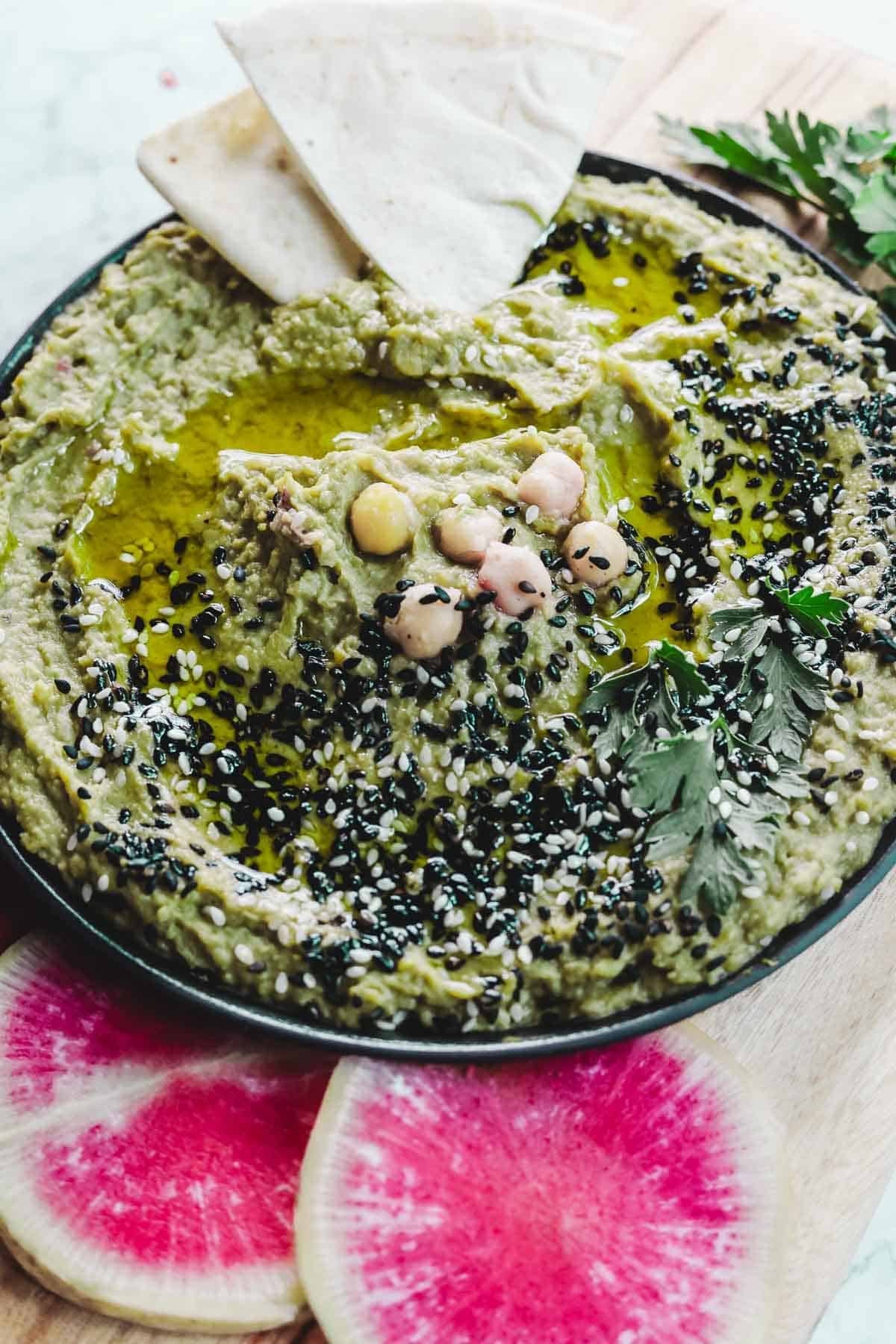 Creamy avocado hummus in a bowl with toppings