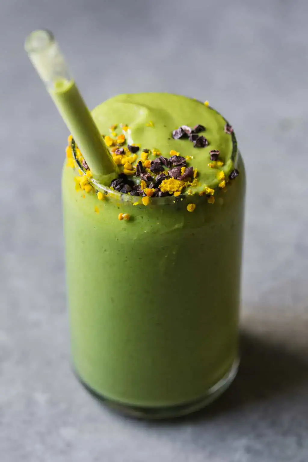 Creamy avocado smoothie in a glass topped with cacao nibs