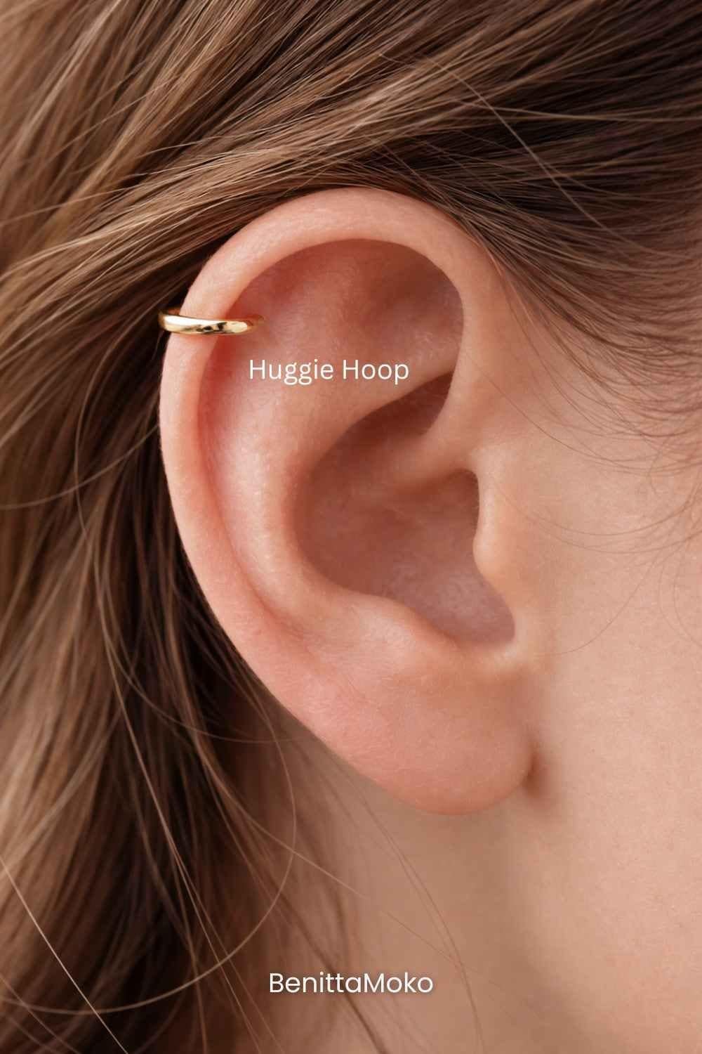 Gold huggie hoop in helix piercing, close-up of ear with minimal cartilage jewelry in warm natural tones