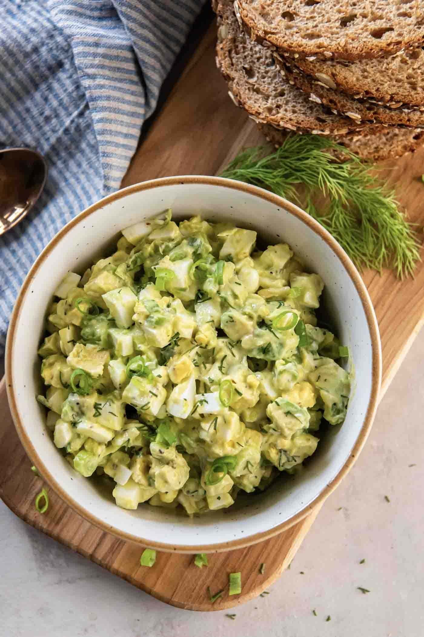Avocado egg salad served in a bowl with fresh herbs