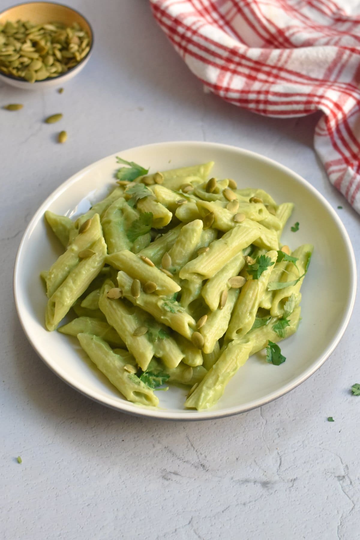 Creamy avocado pasta in a bowl topped with herbs