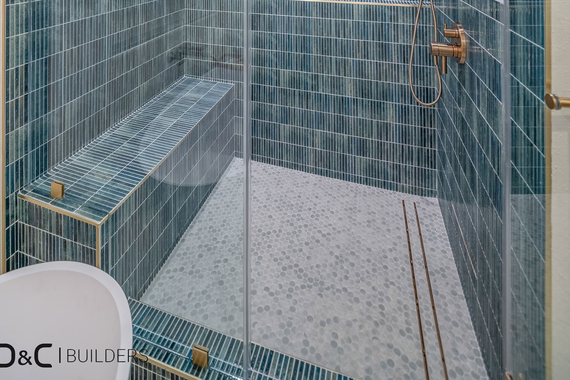 Shower corner with green tile and gold fixture