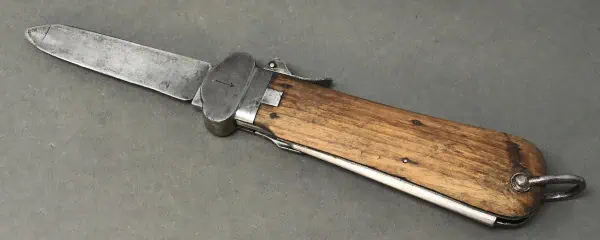 A knife with a wooden handle and metal blade on a gray background.