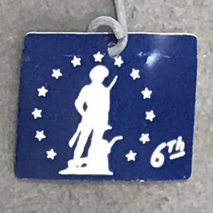 Vintage-style blue tag featuring a white silhouette of a soldier with a raised arm, surrounded by st.