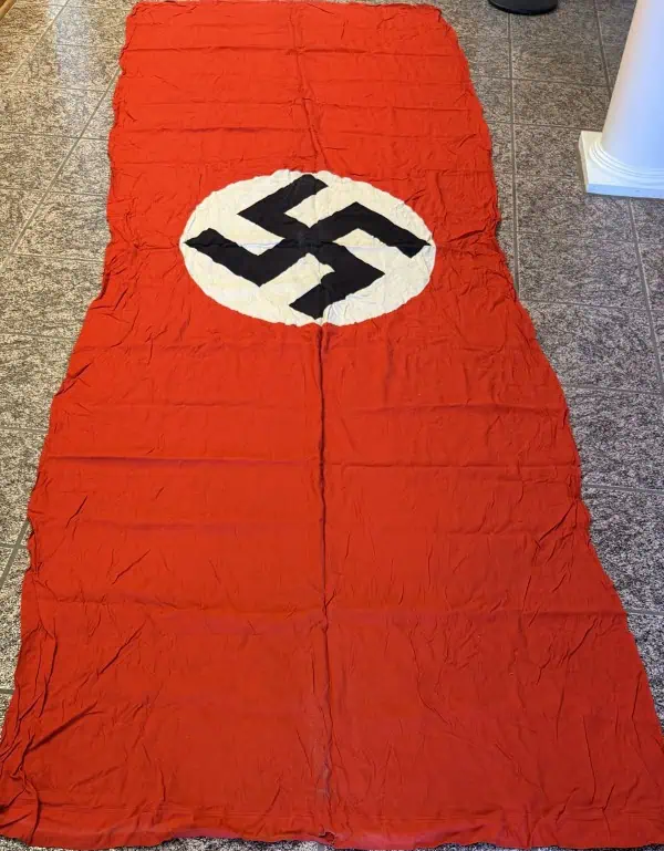Nazi flag with swastika symbol on red background, displayed on the floor.